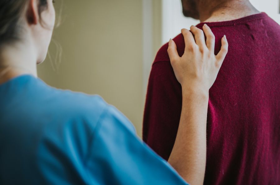 Mujer pone la mano en el hombro de un hombre para ofrecerle su ayuda