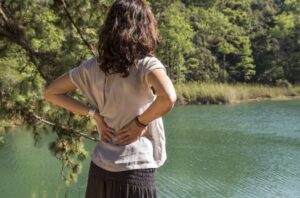 Mujer con las manos en la espalda mirando el paisaje de un río
