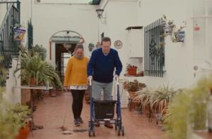 Hombre con andador y mujer en el patio de su casa